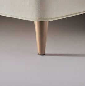 Close-up of a beige upholstered chair leg on a neutral background