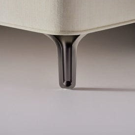 Close-up of a beige upholstered chair with a metal leg on a neutral background