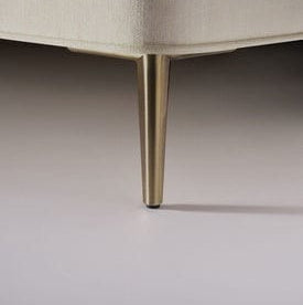 Close-up of a beige upholstered chair leg on a neutral background