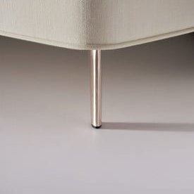 Close-up of a beige upholstered chair leg on a plain background