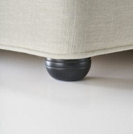 Close-up of a black furniture leg on a beige sofa base.