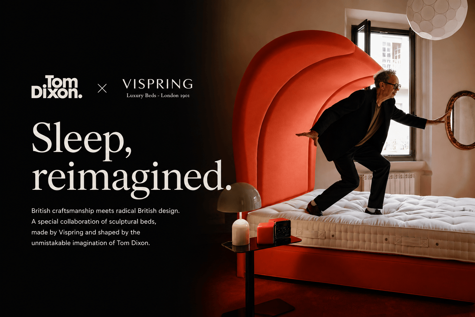 A lifestyle promotional photo for the Tom Dixon x Vispring collaboration, featuring a man in a black suit playfully stepping off a white mattress on a bold, sculptural rust-red bed frame in a dimly lit bedroom. The left side of the image features a black background with white text reading 'Sleep, reimagined.